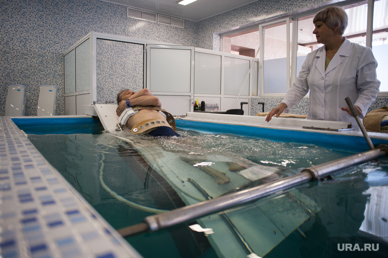 Погружение пациента в мини-бассейн для прохождения процедуры вытяжки позвоночника