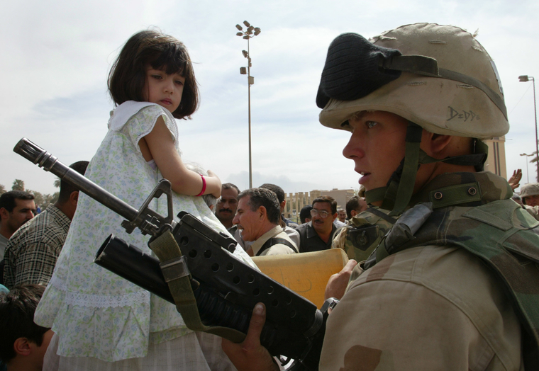 12 апреля 2003 года. Иракская девочка смотрит на американского солдата, наблюдающего за митингом с требованием восстановить закон и порядок в центре Багдада. В тот момент Гаранич был прикреплен к подразделению американских и британских войск