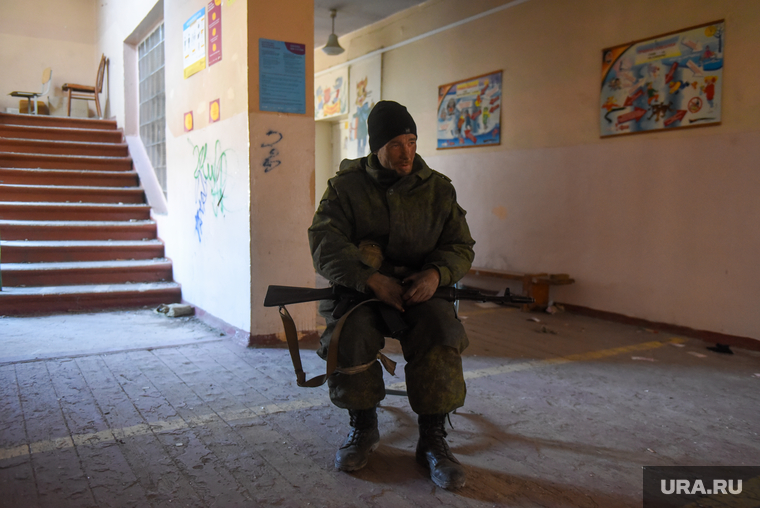 Военнослужащий милиции ДНР сидит на стуле в коридоре освобожденной школы