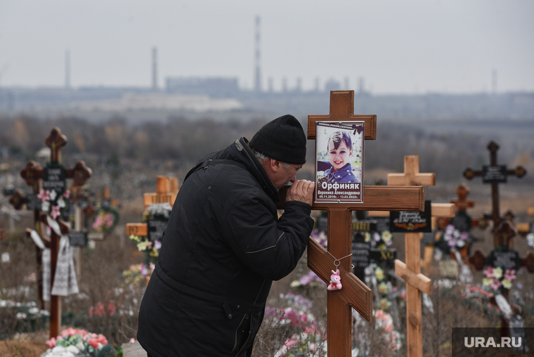 Мужчина плачет над могилой погибшей при обстрелах Мариуполя девочки