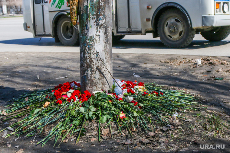 Место гибели семилетнего ребенка под колесами автобуса в Кургане, пазик, гвоздики, цветы у дороги, колеса автобуса