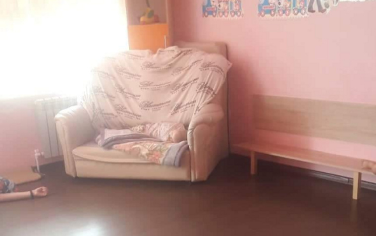 На фото видно спящего на кресле ребенка и няню — на полу