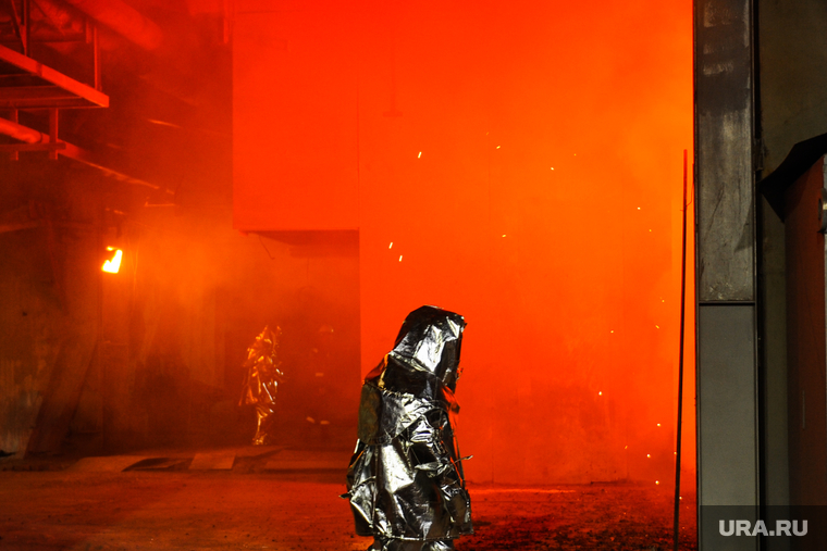 Работники ходят по территории в огнеупорных костюмах