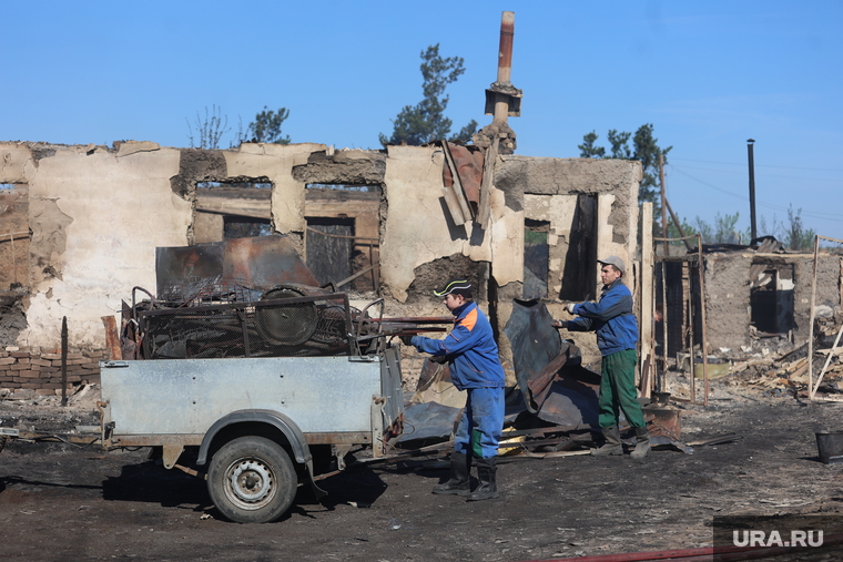 Местные жители возвращаются к сгоревшим постройкам, чтобы разобрать завалы