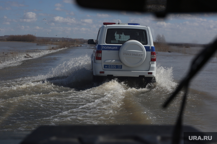 Полиция помогает людям, оказавшимся на дороге, перебраться на «твердую землю». Дороги полностью затоплены.
