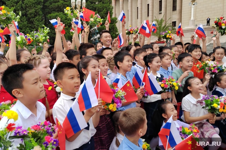 Оркестр играет российский гимн, «Подмосковные вечера», дети с флагами Китая и России кричат «Добро пожаловать»