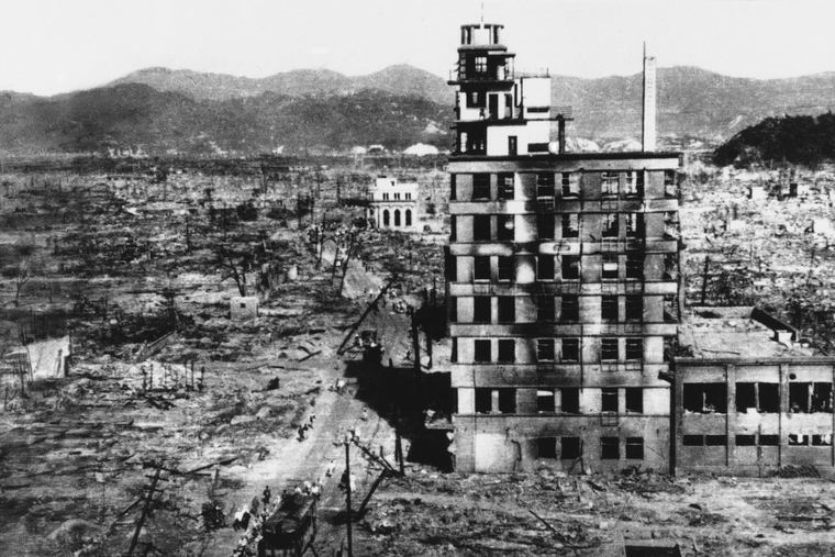 Выжившие проходят мимо одного из немногих зданий, сохранившихся в 1945 году, после того на Хиросиму была сброшена атомная бомба