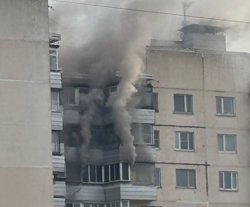 Из окна горящей квартиры валит густой черный дым