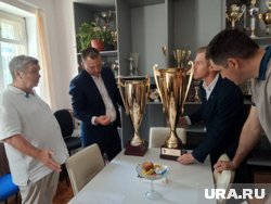 Николай Власов (слева) демонстрирует Кириллу Матвееву, Антону Рыжему и Александру Назарову кубки, завоеванные воспитанниками спортшколы