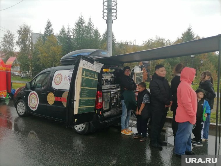 Гости праздника ищут укрытия у мобильной кофейни 