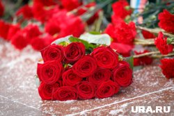 У мемориальной таблички также стоят две вазы с красными розами