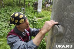 Илья Сидоров очищает от краски надгробие