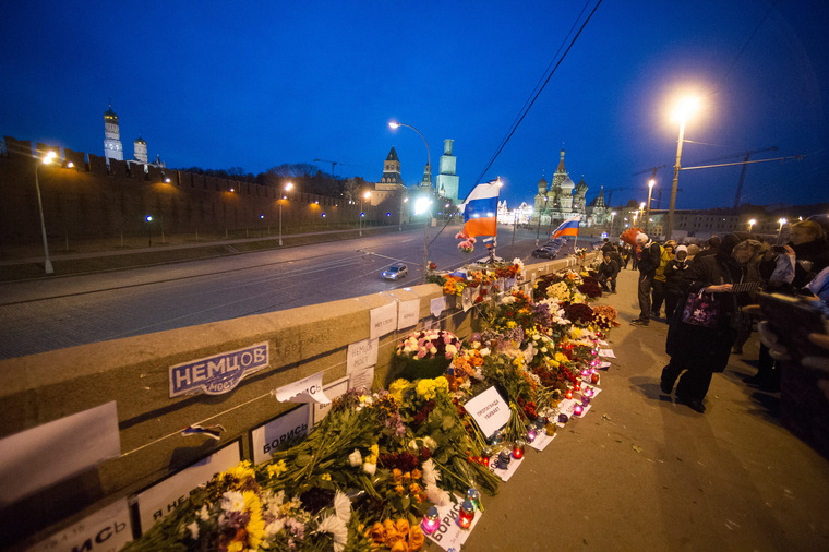 Люди несут цветы на место гибели Бориса Немцова после того, как мемориал был разрушен ночью. Москва, немцов
