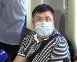 Денис Синяк скрывает лицо за медицинской маской