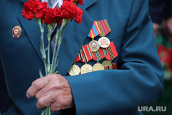 Laying flowers at the memorial of the Eternal Flame on the day of memory and sorrow, on the day the Second World War began.  Kurgan, carnations, veteran, medals and orders, WWII veterans