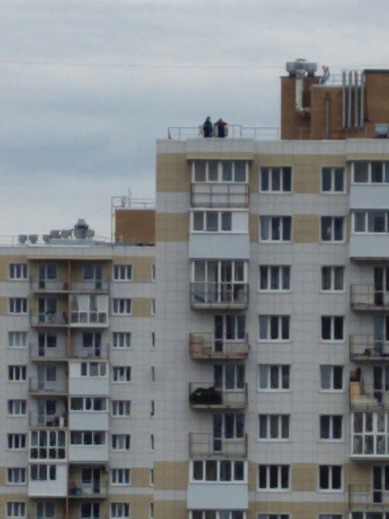 Подростки смотря вниз с крыши многоэтажки